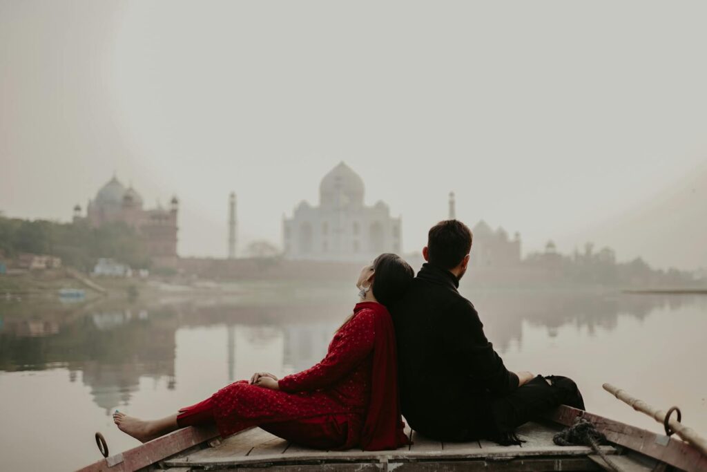 A couple sitting on a boat with the iconic Taj Mahal in the background, evoking a romantic and serene mood.